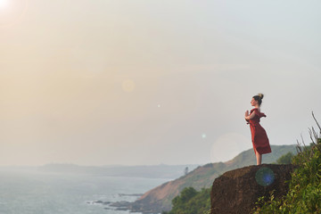 Young girl practices yoga in a red dress on a mountain in India