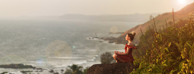 Young girl practices yoga in a red dress on a mountain in India