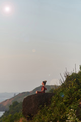 Fototapeta premium Young girl practices yoga in a red dress on a mountain in India