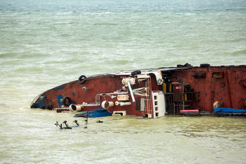 wrecked cargo ship captain bridge of a ship half sunken in sea water.