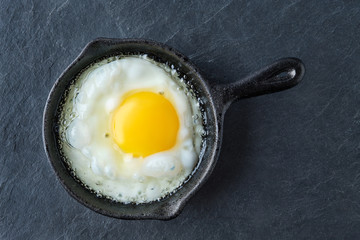 Top view of fried egg in small cast-iron skillet. Making scrambled eggs.