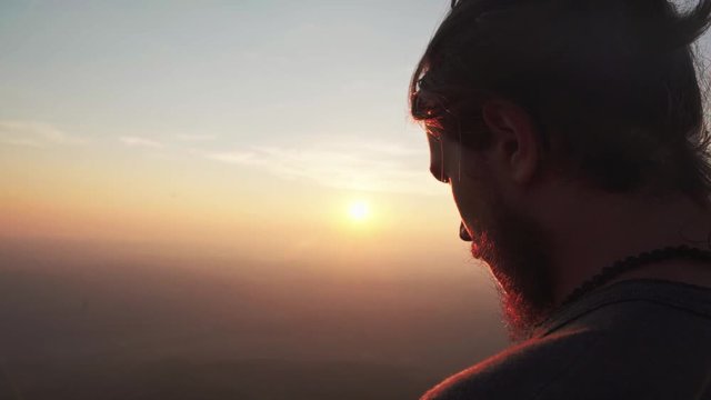 Close up head shot from the back in sunset of a man looking down from a mountain