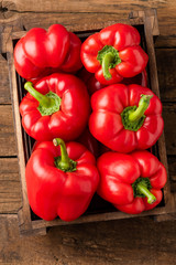 Red sweet pepper in box on old wooden background. Top view