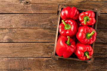 Red bell pepper in box on vintage wooden table with copyspace. Top view