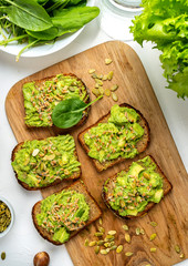 Sandwiches with avocado guacamole on a wooden board on the table. Top view. Close-up.