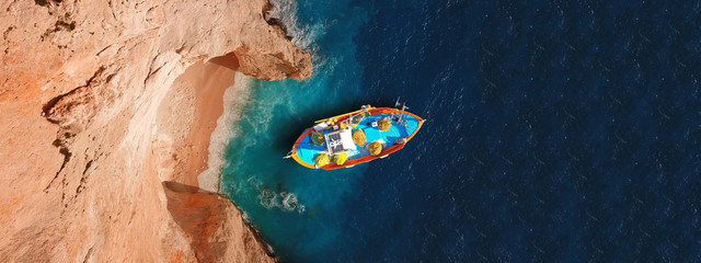 Aerial drone top down photo of traditional wooden fishing boat docked in Zakynthos island, Ionian, Greece