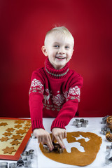 A child cuts a gingerbread cookie with a cookie cutter a snowflakes on a white background. Little...