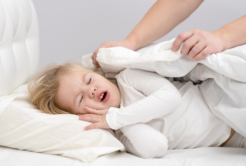 Fototapeta na wymiar little girl mom hides the blanket on the bed