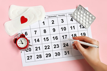 Menstruation calendar with pads, alarm clock, hormonal contraceptive pills. Female's menstrual cycle concept. Menstrual retardation concept - obrazy, fototapety, plakaty