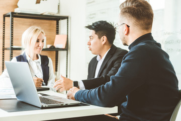 A team of young businessmen working and communicating together in an office. Corporate businessteam and manager in a meeting.