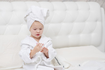 little cute girl painting her nails on the bed