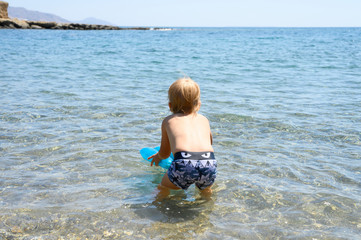 three year old little boy having fun at summer vacation in sea with his family