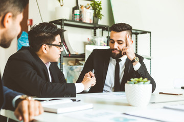A team of young businessmen working and communicating together in an office. Corporate businessteam and manager in a meeting.