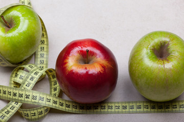 green and red big apple photographed with a tailor on a light background