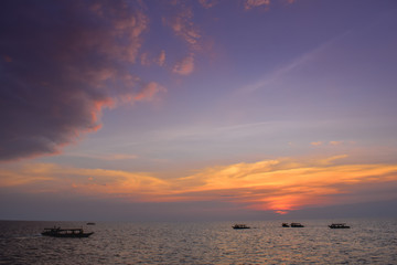 Group of boats on a wide sea during beautiful pink and blue sunset in Thailand Asia