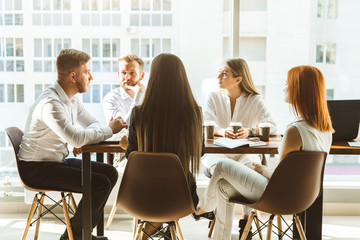 A team of young businessmen working and communicating together in an office. Corporate businessteam and manager in a meeting.