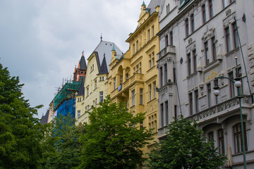 Facade of typical colorful czech houses with trees at the foreground in Prague, Czech Republic