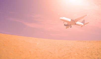 Fototapeta na wymiar The plane over the desert at sunset in the evening. Scenery transport.