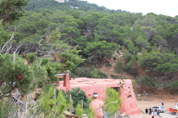 Fototapeta na wymiar red cottage built on the slopes of a green Ibizan hill in cala salada