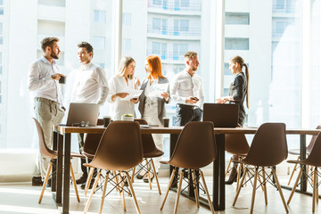 A team of young businessmen working and communicating together in an office. Corporate businessteam and manager in a meeting. desktop against the background of the pan window, free space for text