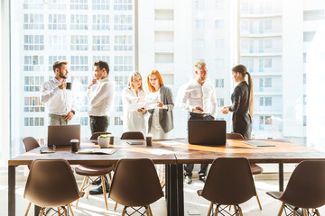 A team of young businessmen working and communicating together in an office. Corporate businessteam and manager in a meeting. desktop against the background of the pan window, free space for text