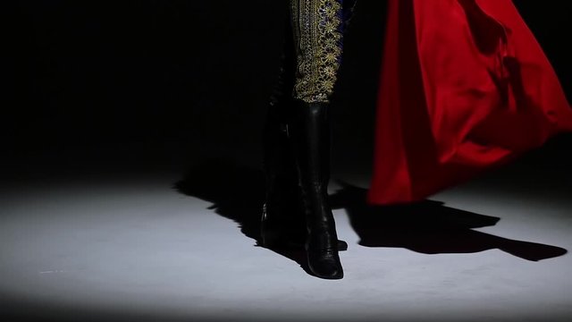 Torero in blue and gold suit or typical spanish bullfighter isolated spotlight on a black background. Close up of legs, slow motion.