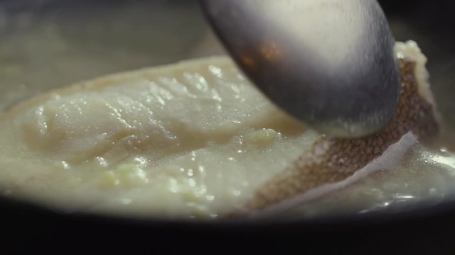 Close-up of halibut fillet cooking in boiling seafood broth