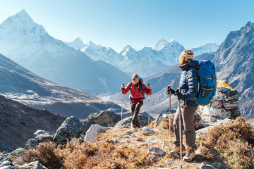 Koppel volgt Everest Base Camp-trekkingroute in de buurt van Dughla 4620m. Backpackers die rugzakken dragen en trekkingstokken gebruiken en genieten van uitzicht op de vallei met Ama Dablam 6812 m piek