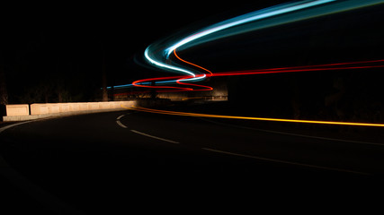 Long exposure of sweeping lights of traffic on a winding road, with copy space.