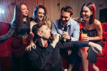 young and happy caucasian friends spend party time in karaoke bar, sing and have fun together,...