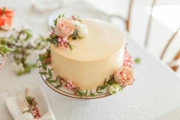 Obraz na płótnie Canvas Wedding white cake with flowers, ranunculus and greenery on the table. Boho wedding decorations