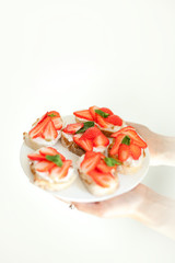 Sweet cheese and strawberry toasts on the white plate on neutral background