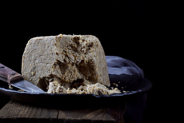 Big piece of sunflower and sesame halva on wooden table against black background. Eastern dessert