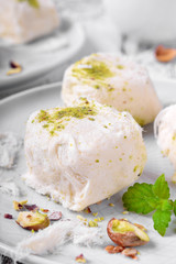 Cotton candy with pistachio on ceramic plate on white wooden table