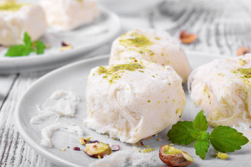 Cotton candy with pistachio on ceramic plate on white wooden table