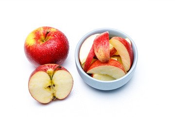 Apfel Stücke in einer hell blauen Schale, ein halber Apfel und ein ganzer Apfel mit Wasser Perlen