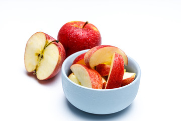 Apfel Stücke in einer hell blauen Schale, ein halber Apfel und ein ganzer Apfel mit Wasser Perlen von oben