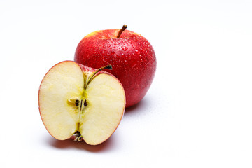 Ein halber Apfel durchgeschnitten mit Kernen und Stil im Hintergrund ein weterer Apfel mit Wasser Perlen