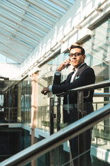 Portrait of a businessman in suit are standing on the background of glass offices.