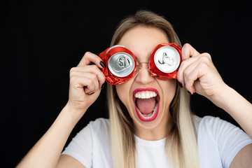 Screaming woman with red lips and cans holding on her face as glasses. Black background