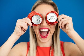 woman holding as glasses cans. Blue background. Red lips, big smile
