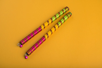 Dandiya sticks on a yellow background. Raas Garba or Dandiya Raas is the traditional folk dance...