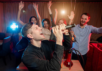 clubber man emotionally singing in microphone, wearing black shirt, have fun in karaoke bar,...