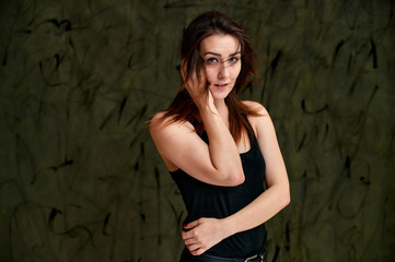 Beauty concept, stylish portrait. Photo of a pretty glamorous brunette girl in a black t-shirt with flying hair on a gray fashionable original background.