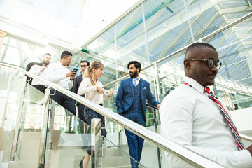 young business people arego down the stairs and talking on the background of glass offices. Corporate businessteam and manager in a meeting.