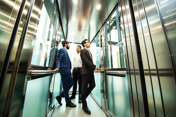Business team group going on elevator. Business people in a large glass elevator in a modern office. Corporate businessteam and manager in a meeting. © xartproduction