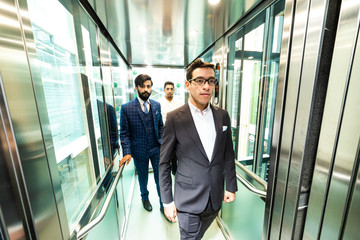 Business team group going on elevator. Business people in a large glass elevator in a modern office. Corporate businessteam and manager in a meeting.