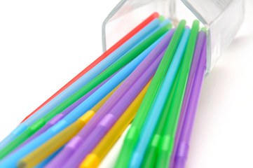 Multicolored tubules for drinks in transparent glass bottle on white background. cocktail day concept