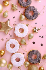 Top view of christmas composition decoration of snowflakes, stars, confetti, balls, golden and white donuts on a pink background. Christmas and New Year happy holiday concept. Flat lay.