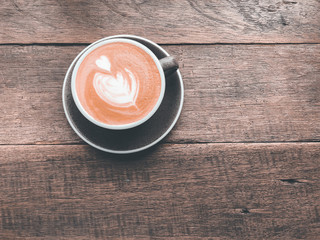 Top view of Latte art coffee placed in ceramics mug and wooden table.